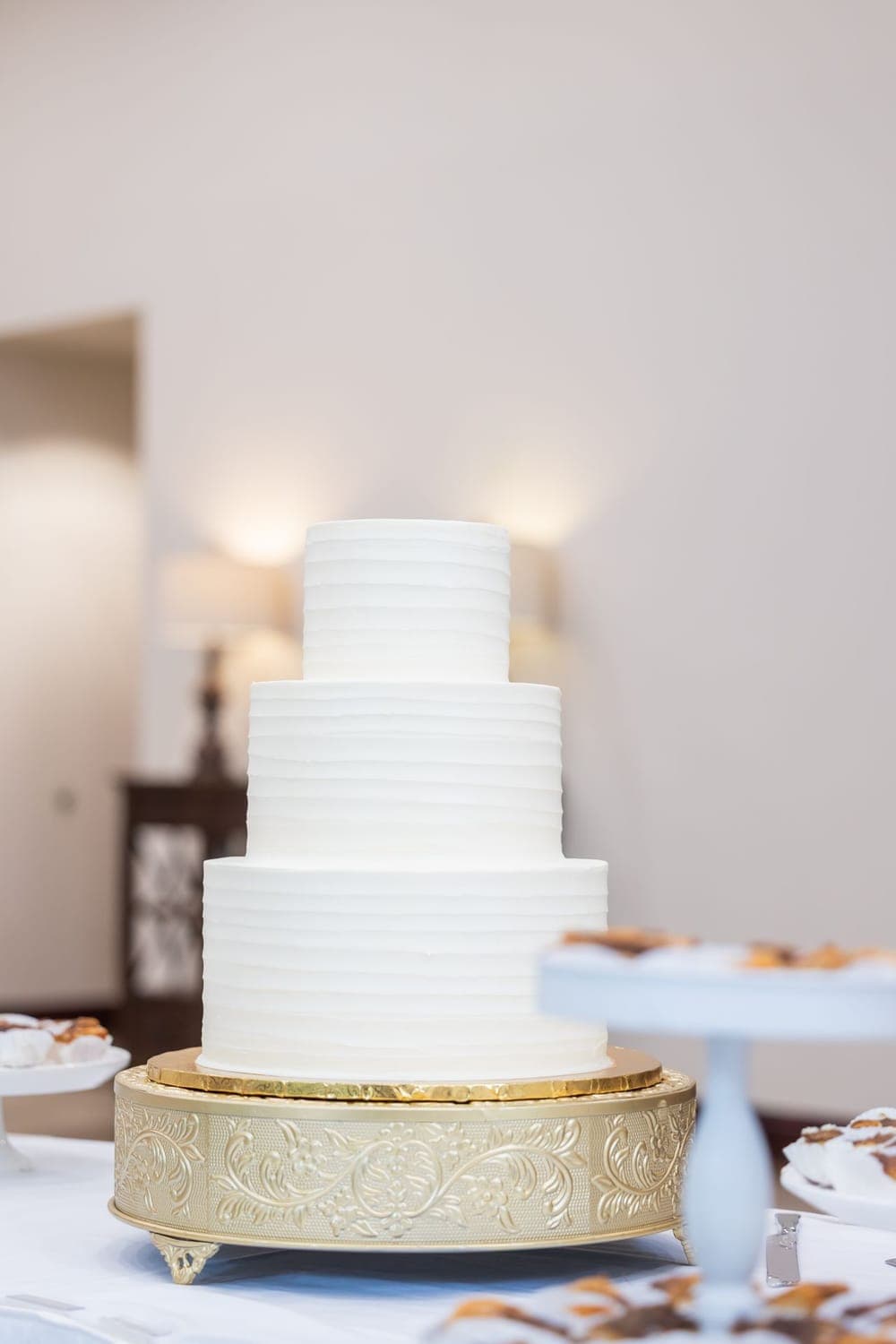 Mehrstöckige weiße Hochzeitstorte auf goldenem Tortenständer
