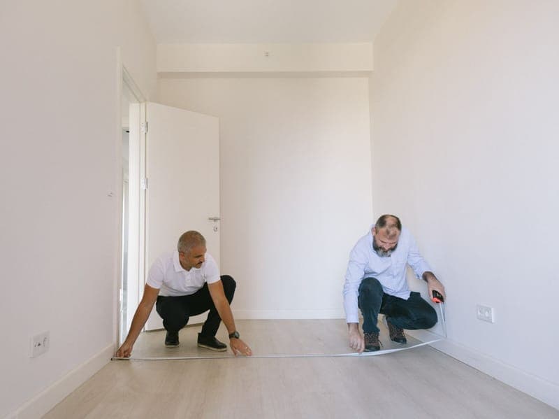 Zwei Handwerker messen einen leeren Raum aus